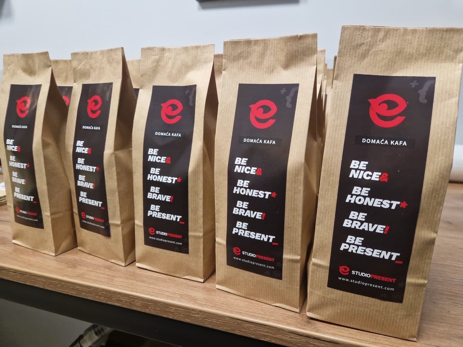 Pet kesa kafe sa etiketom Studio Present, poređane na polici